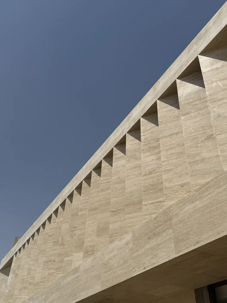 Villa Louve under construction — sawtooth stone soffit against the sky
